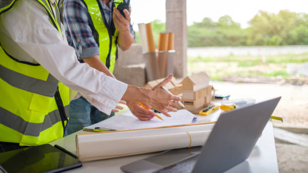 istock Engineers and architects in safety helmet working with blueprints and discussing project at construction site. 2161995920