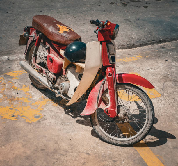 Retro red motorcycle parked on a street with old stone pavement and walls.