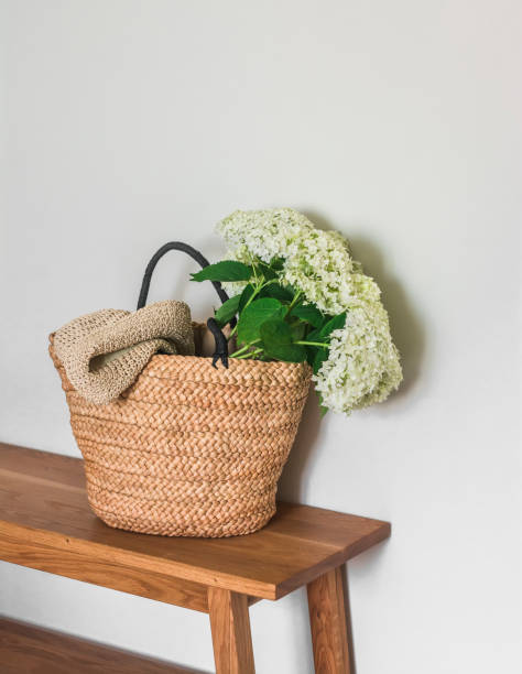 A wicker basket bag with a bouquet of hydrangeas on a wooden bench
