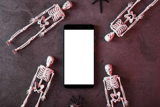 istock Skeletons around a smartphone with a white display on a dark background. 2162013063