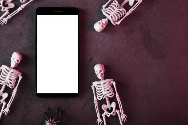 istock Skeletons around a smartphone with a white display on a dark background. 2162013079