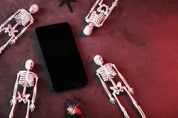 istock Skeletons around a smartphone with a white display on a dark background. 2162013091