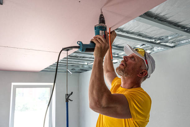 istock The worker screwing plasterboard to the ceiling. He is using special electric screwdriver and drywall lift. A red plasterboard improve the fire resistance of ceiling structures. 2162013520