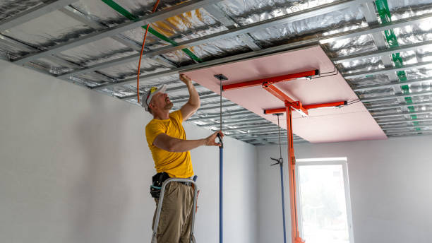 istock The worker screwing plasterboard to the ceiling. He is using special electric screwdriver and drywall lift. A red plasterboard improve the fire resistance of ceiling structures. 2162013522