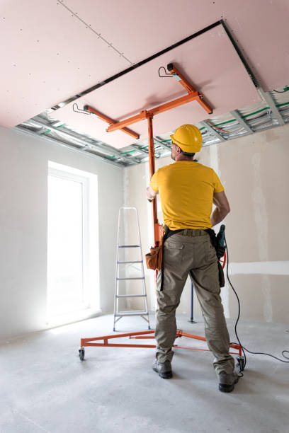 istock The worker screwing plasterboard to the ceiling. He is using special electric screwdriver and drywall lift. A red plasterboard improve the fire resistance of ceiling structures. 2162013605