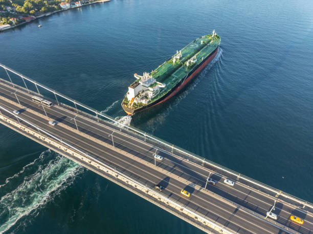 istock Aerial view of a cargo ship passing under bridge. Cargo Ship Beneath Bridge. 2162017640