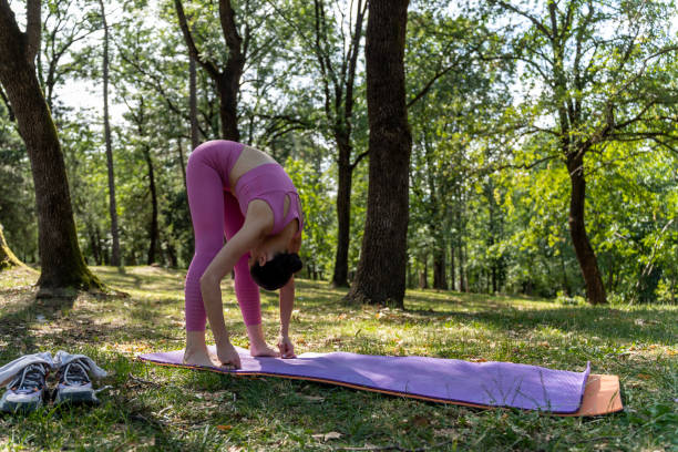 istock Woman practicing yoga exercises on mat in public park. 2162021856
