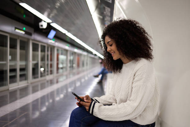 istock Young woman smiling and using smartphone while waiting for subway 2162030144