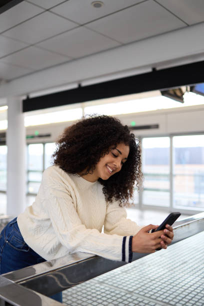 istock Cheerful young ethnic woman leaning on railing and using smartphone 2162030261