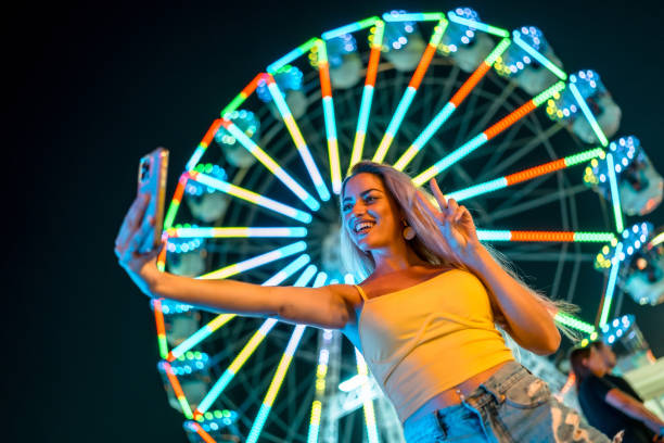 istock Woman making selfie gesturing success at amusement park at night 2162038507