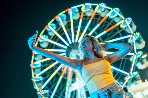 istock Happy woman taking selfie next to illuminated ferris wheel 2162038577