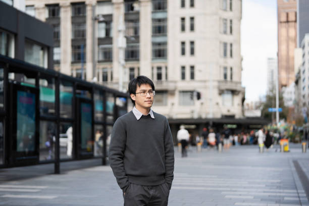 istock Young Asian man strolling through a bustling city square. 2162041494