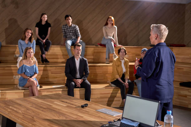 istock female financial coach gesturing talks at conference or forum. students in large auditorium 2162047711