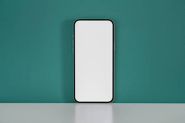 istock Smartphone with a blank screen placed on a white desk against a green wall 2162050217