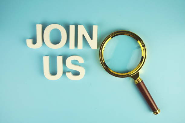 istock Join Us alphabet letters with magnifying glass on blue background 2162051890