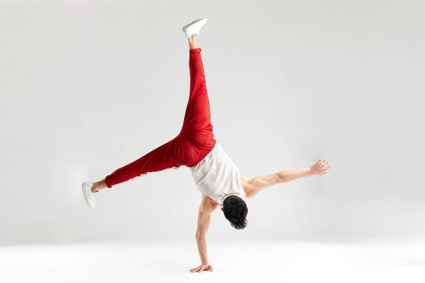 istock Young man in red sweatpants doing a handstand on hands on white background 2162052753