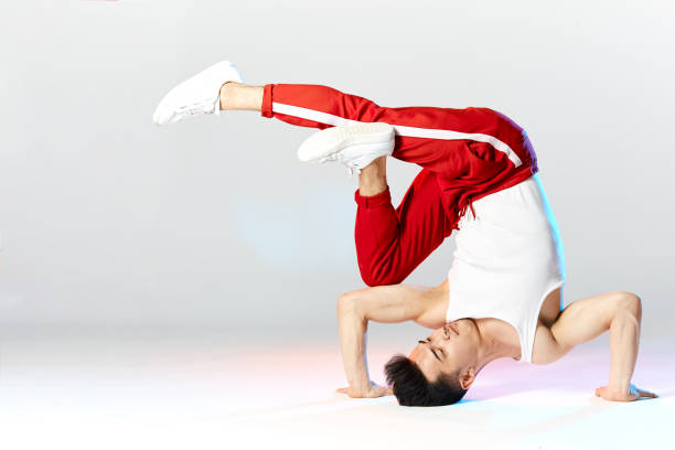 A woman is doing a handstand on a blue background. Scene is energetic and dynamic