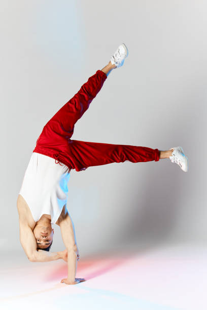 istock Young man in red sweatpants doing a handstand on hands on white background 2162052774