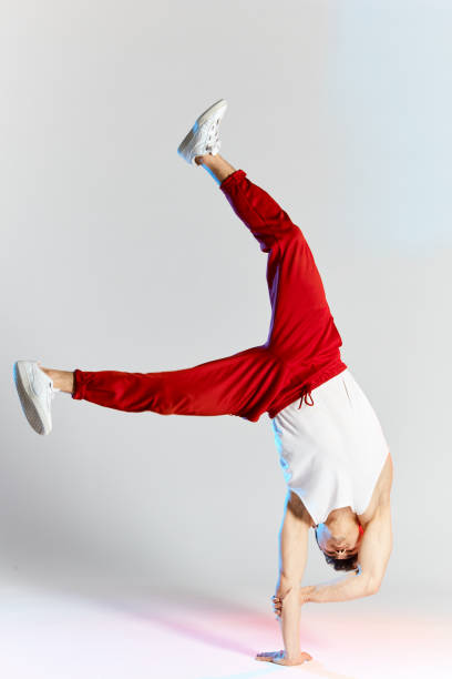 istock Young man in red sweatpants doing a handstand on hands on white background 2162052777