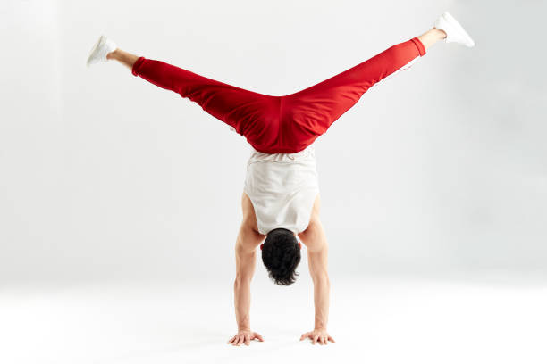 istock Young man in red sweatpants doing a handstand on hands on white background 2162052793
