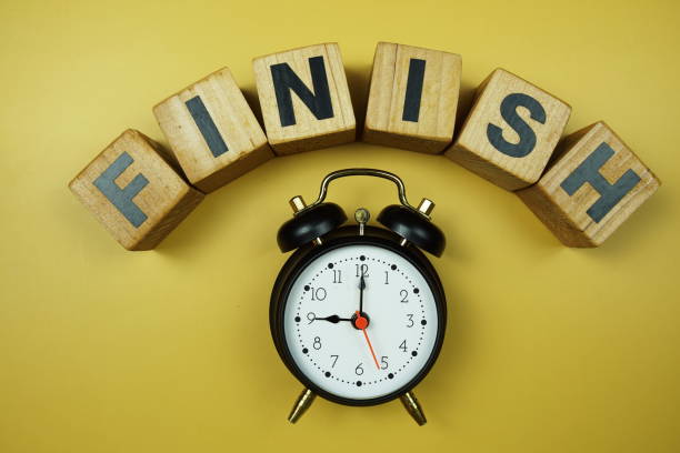 istock Finish alphabet letters and alarm clock top view on yellow background 2162052828
