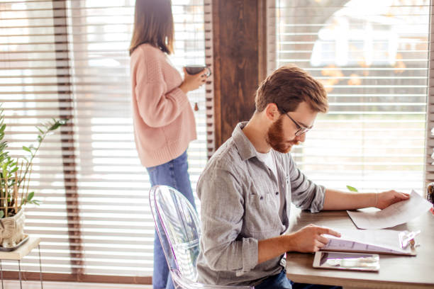 istock Young european man reading documents while sitting at table at home 2162053137