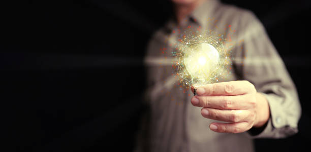 istock Idea and solution for business and technology. A man holds a glowing lightbulb with network and many digital gear icons around it 2162058552