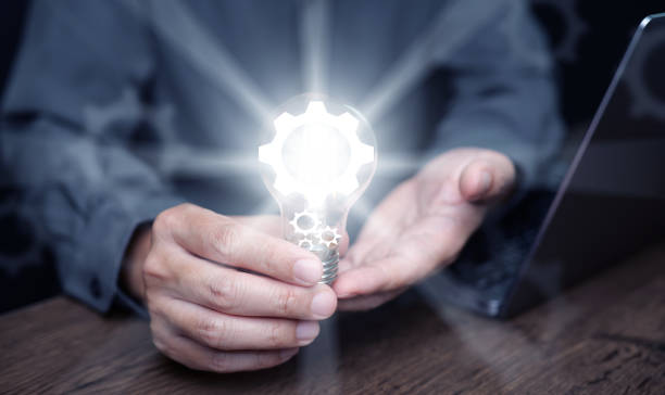 istock Idea and solution for business and technology concept. A man holds a glowing lightbulb with digital gear icons in it 2162058556