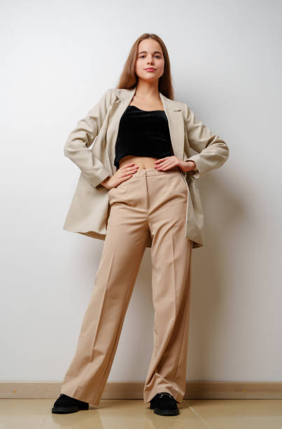 istock Young woman model posing in beige suit against white background 2162068544