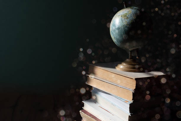 A simple composition of a stack of books and earth globe with copy space on black background