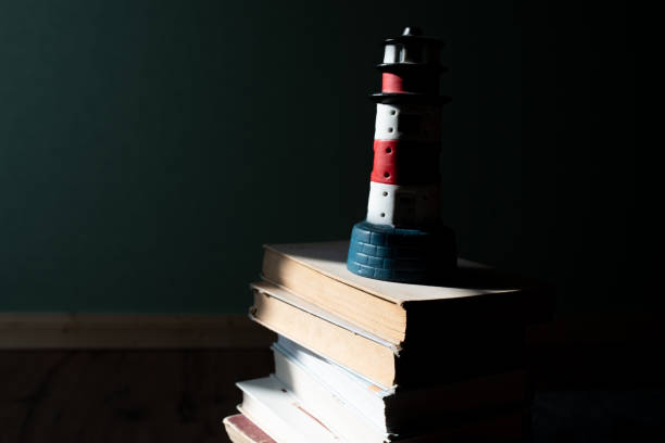 Hand holding a small ceramic lighthouse souvenir, featuring a blurred backdrop of the sea and trees under a bright sunny sky, capturing the essence of summer travel and coastal serenity