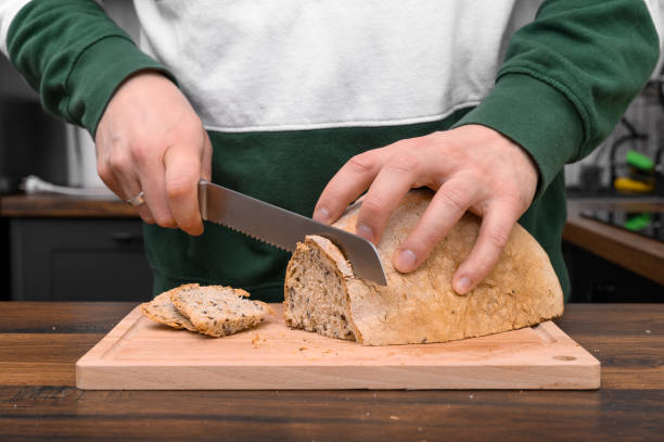 istock Cutting homemade sourdough rye bread with a sharp serrated knife, bread knife. 2162071890
