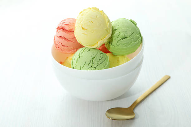 Bowl with ice cream scoops on white wooden table