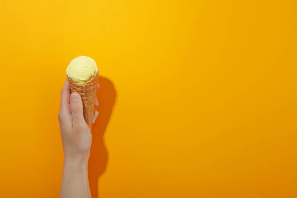 istock Female hand with ice cream on orange background, space for text 2162072359