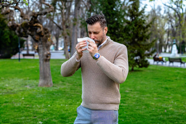 istock Young man with allergies sneezing in a park 2162072567