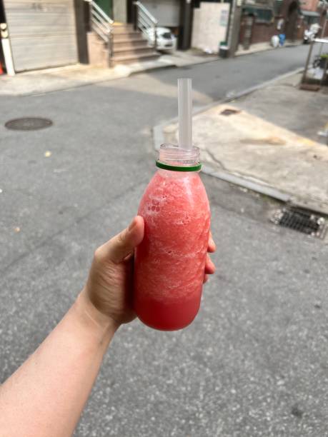 istock female hands holding a bottle with red smoothies, Watermelon juice 2162075762