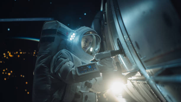 istock Female Space Technician Mending a Panel on an International Space Station with an Automatic Screw Gun. Fearless Astronaut Working in Outer Space with Gorgeous Blue Planet in the Background 2162076804