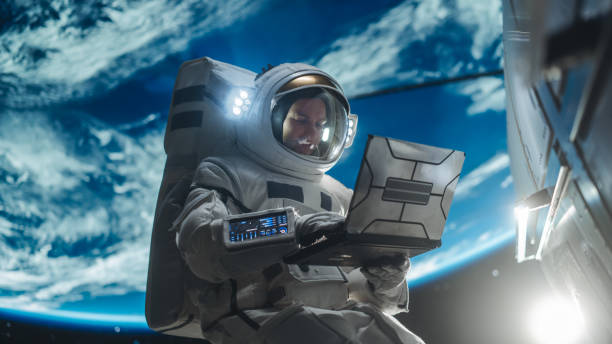 istock Male Astronaut Using a Laptop to Wirelessly Connect to a Satellite. Spaceman Working on a Device in Open Space Outside Earth Atmosphere. Professional Engineer Undertaking Service, Maintenance Job 2162077438