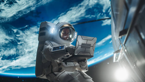 istock Male Astronaut Using a Laptop to Wirelessly Connect to a Satellite. Spaceman Working on a Device in Open Space Outside Earth Atmosphere. Professional Engineer Undertaking Service and Maintenance Job 2162077459