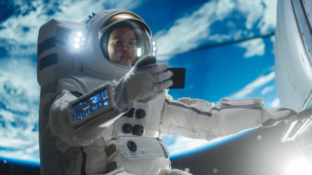 istock Male Astronaut Holding Smartphone in Horizontal Position, Watching a Video on Device in Open Space Outside Earth Atmosphere. Professional Engineer Undertaking Satellite Service and Maintenance Job 2162077497