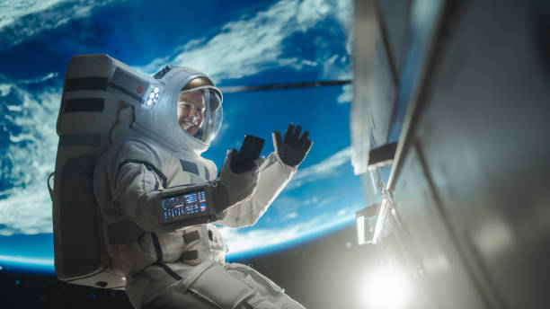 istock Man in a Space Suit Casually Talking on a Phone in Outer Space While Holding on to a Satellite. Astronaut Chatting with Mission Control, Family or Work Colleagues on a Video Call App on a Smartphone 2162077530
