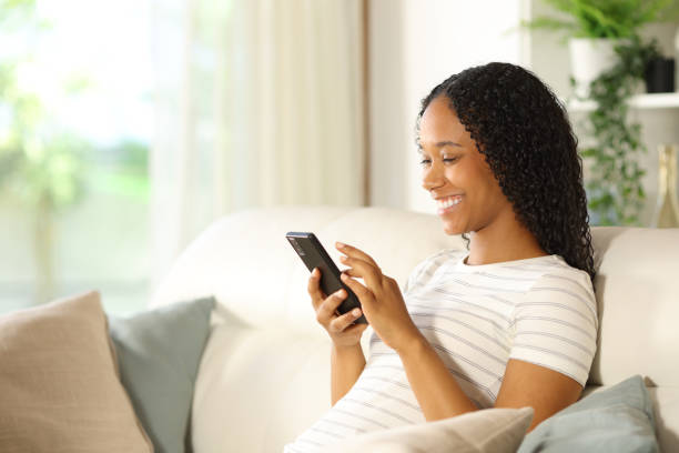 istock Happy black woman using smart phone at home 2162081570