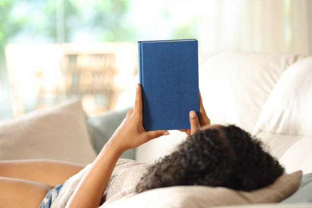 istock Black woman watching blank book cover 2162081819