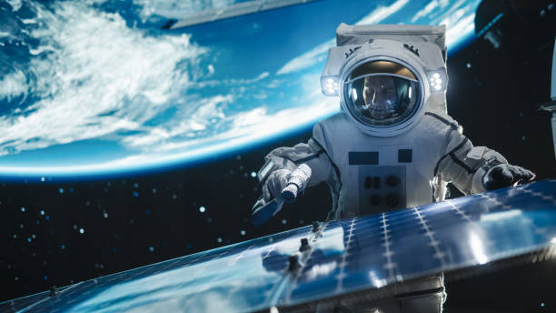 istock Astronaut on an Extravehicular Mission in Outer Space Far From Planet Earth. Courageous Caucasian Man Fixing and Adjusting the Angle on a Solar Panel Module with a Screw Gun Outside the Space Station 2162084327