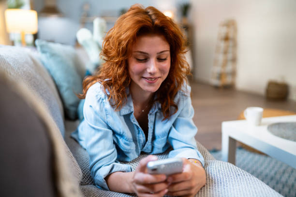 istock Redhead Caucasian woman relaxing on the sofa while using mobile phone 2162085299