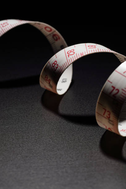 istock White measuring tape isolated on dark background 2162085880
