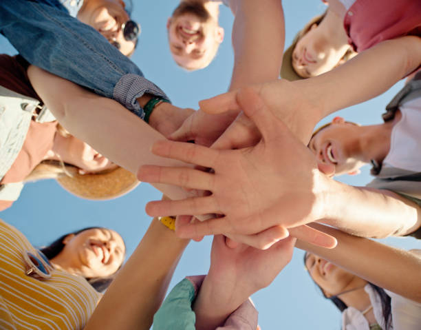 istock Happy, group and hands together with teamwork in unity, motivation or collaboration below blue sky. Closeup or low angle of people piling or touching for community, mission or agreement in solidarity 2162086234