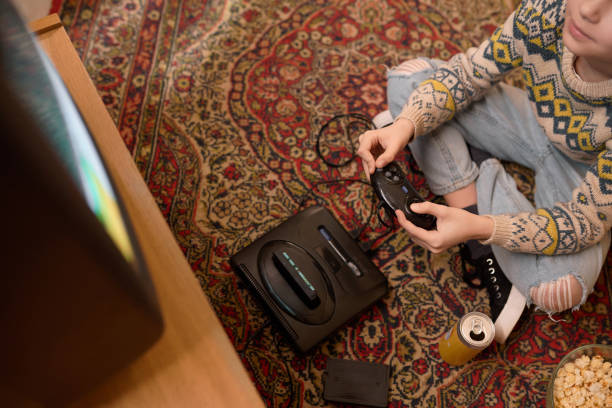 Gothenburg, Sweden - January 07, 2015: A shot from above of a young mans hands holding an old game pad for the Sega Master System. Natural lights.