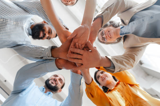 istock Diverse group of business people joining hands in circle selective focus 2162089710