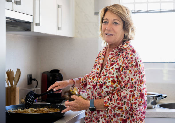 istock Senior woman cooking fried noodles in a modern kitchen. 2162092100
